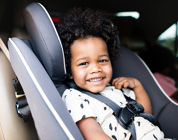 Smilende barn som sitter i bilsete i bil.Foto