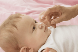 Baby får krem på nesa.Foto