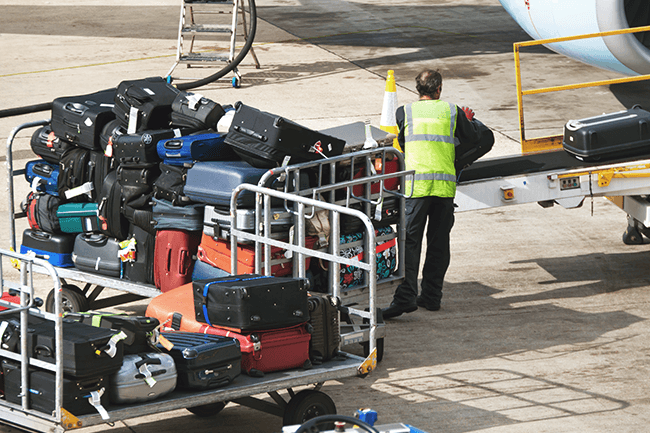 Mann lesser på bagasje på fly.Foto