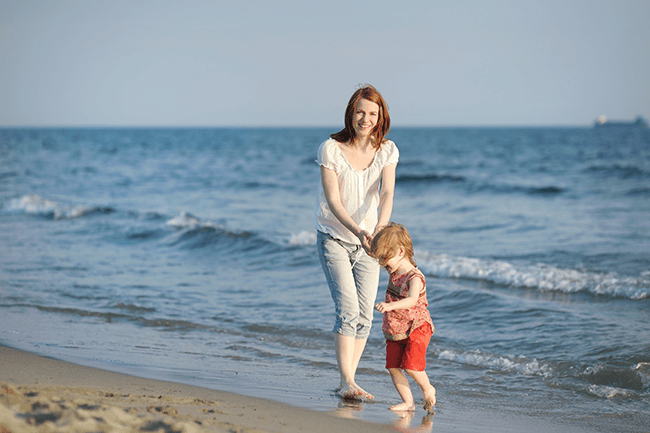 Mor og barn på stranda.Foto