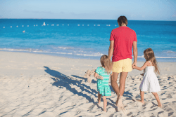 Far og to barn på stranda.Foto.