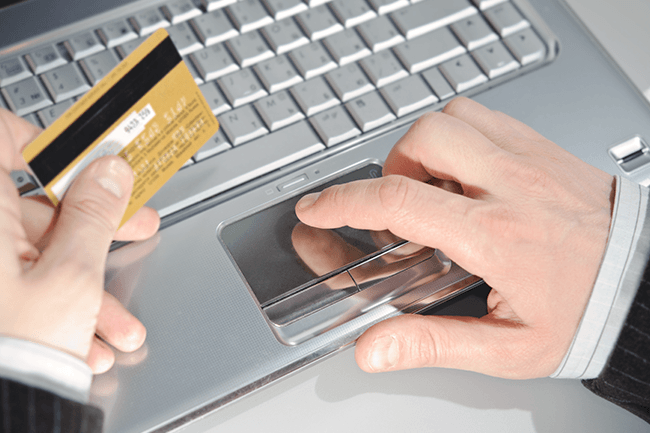 Mann betaler med kredittkort på nett.Foto