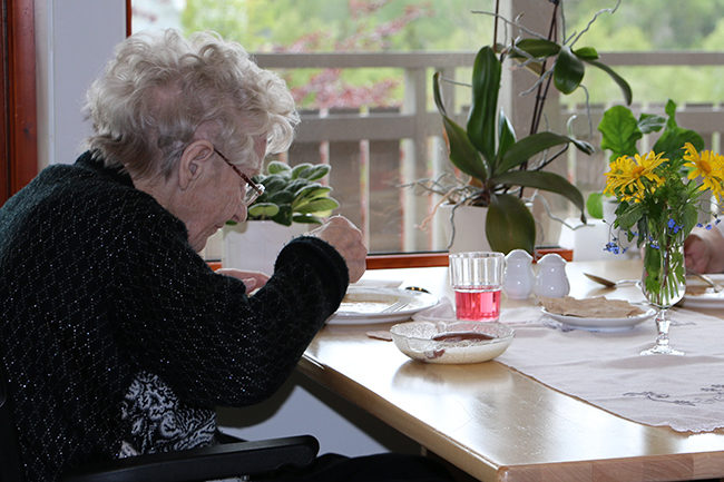 Eldre kvinne ved matbord.Foto