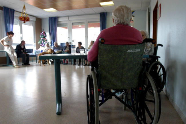 Eldre mann i rullestol på sykehjem.Foto