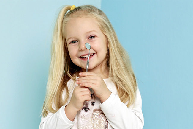 Ung jente med tannlegeinstrumenter.Foto