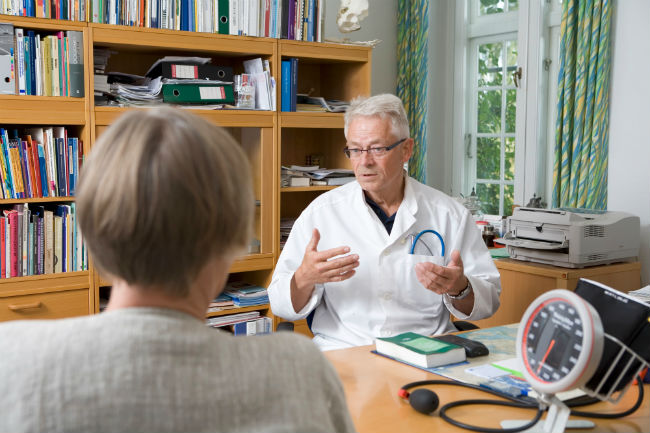 Lege snakker med pasient på legekontor.Foto