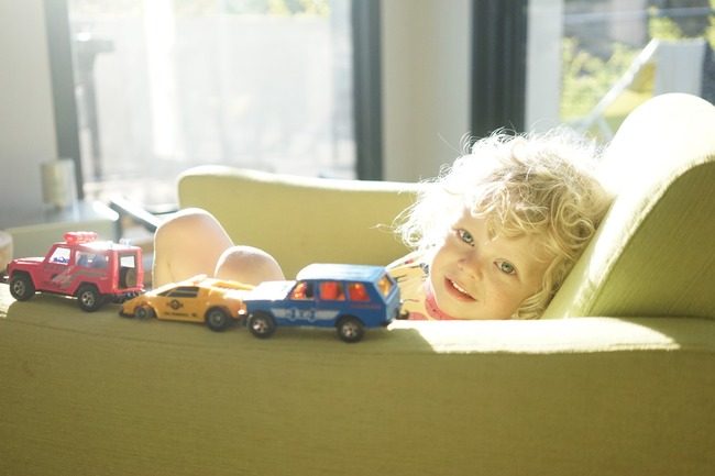 Gutt leker med biler i sofaen.Foto