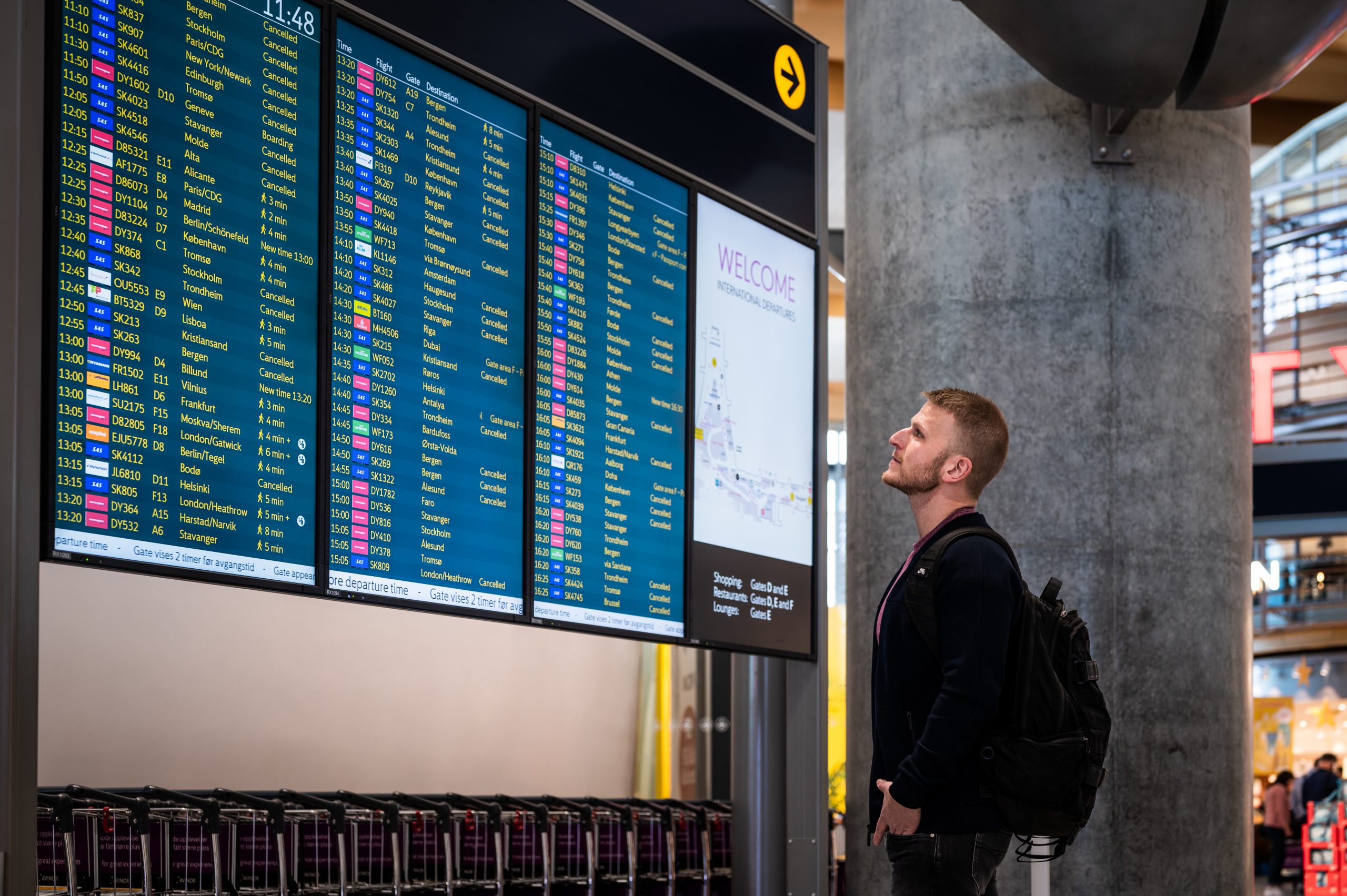 Bilde av en person som står foran en avgangstavle på flyplassen.Foto