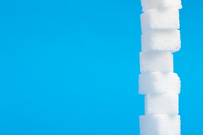 Bilde med blå bakgrunn som viser et stort antall sukkerbiter stablet oppå hverandre.Foto
