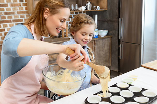 Mor og barn som lager muffins med muffinsformer. 