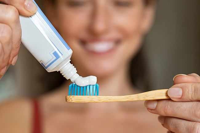 Illustrasjonsbilde av en kvinne som trykker tannkrem på en tannbørste.foto