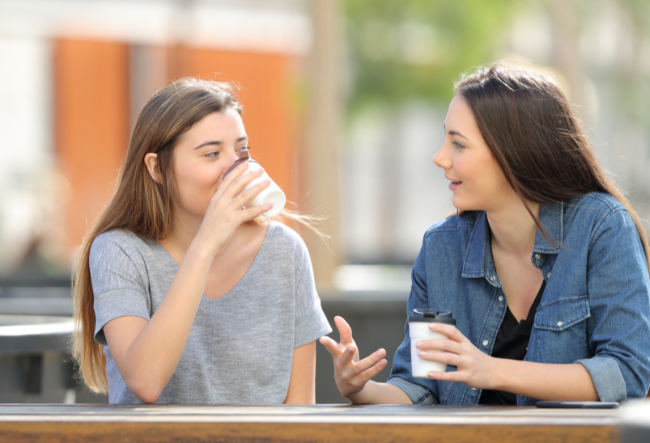 To jenter drikker kaffe og snakker sammen.foto