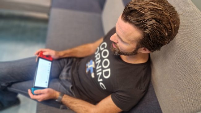 Bilde av Thomas Iversen som sitter i en sofa med en Nintendo Switch i hendene.foto