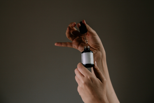 Hender som holder en flaske med pipette.Foto