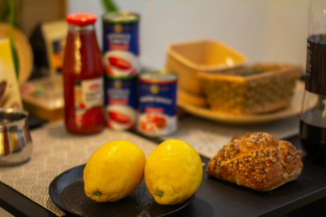 Kjøkkenbenk med matvarer. Sitroner, rundstykke og hermetikk i bakgrunnen.Foto